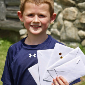 Fast facts: communication is through letter writing. A camper holding up letters from home.