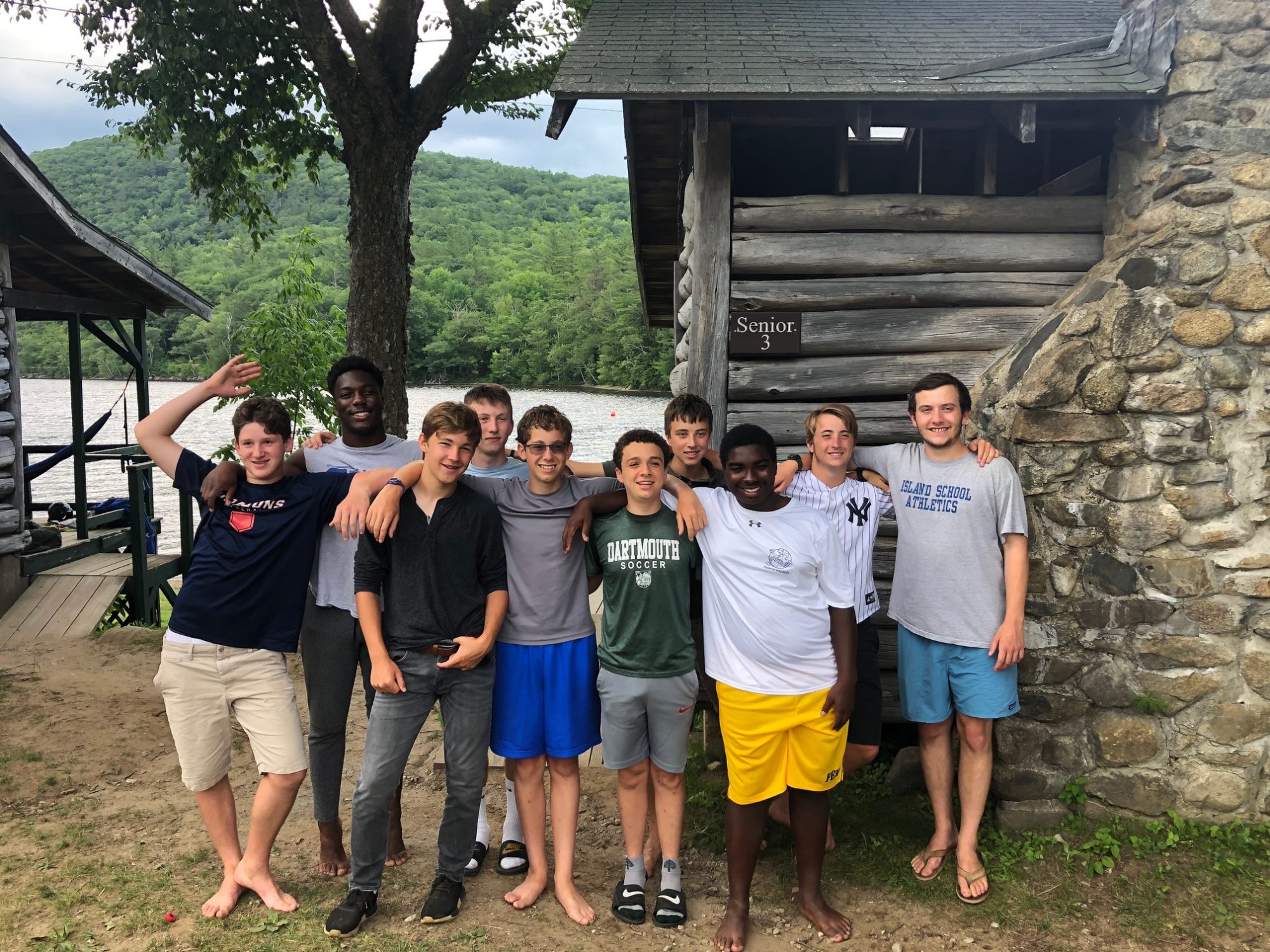 A photo of happy Pemi senior campers in front of a cabin