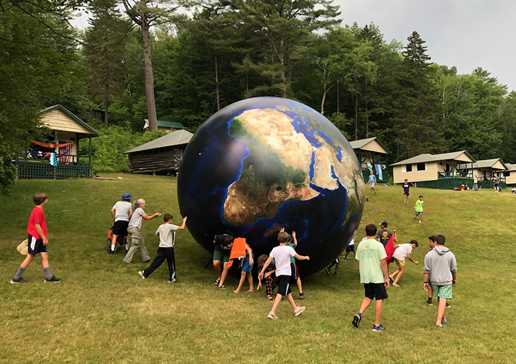 Campers playing with a huge inflatable globe at Pemi